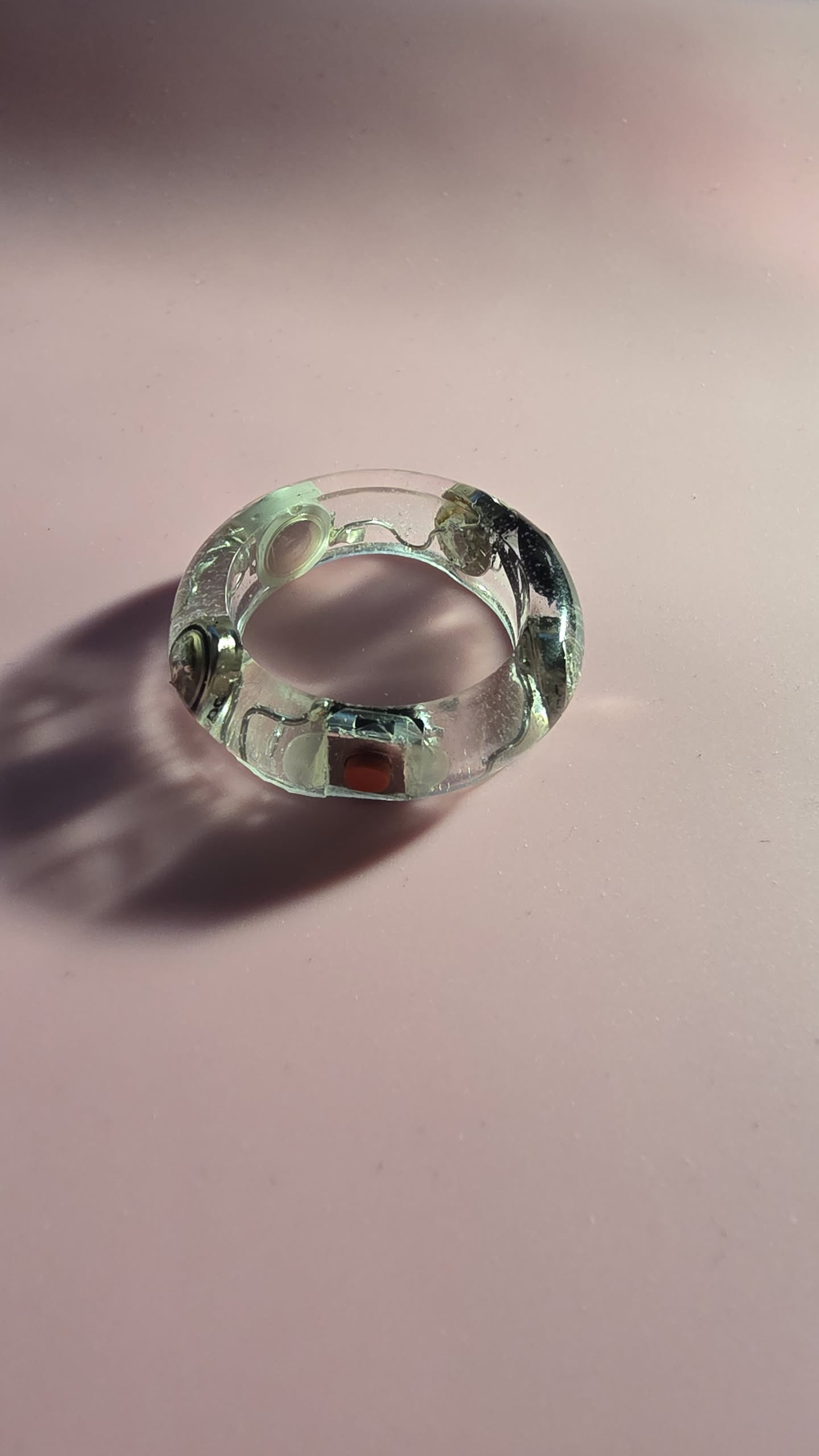 Light Ringz prototype — clear resin ring on pink surface showing internal components